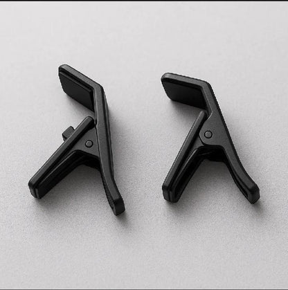 Two black guitar capos on a light gray background

