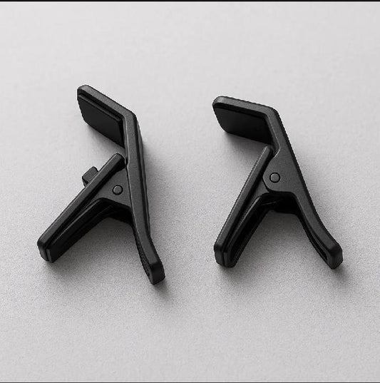 Two black guitar capos on a light gray background

